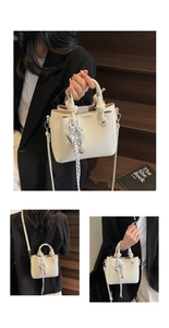Detail of white lychee pattern crossbody bucket bag with knot handle and bow charm