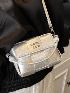 Silver woven crossbody bag with metallic finish and decorative beaded handle strap