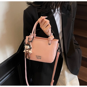 Pink oil wax leather bucket bag with metal logo and cute doll charm accessory
