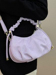 Lilac snake-embossed crescent handbag with pleated handle and gold hardware on a model