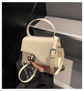 Dettaglio della borsa in pelle verniciata bianco crema con fibbia in metallo a forma di cuore