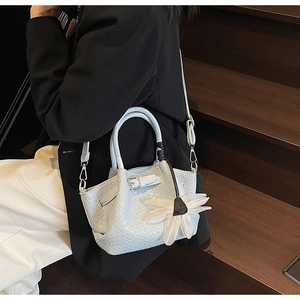 Détail du sac à main tressé bleu-gris clair avec breloque fleur blanche et bandoulière