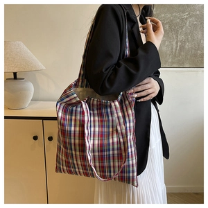 Detailed view of the large capacity plaid tote bag worn over the shoulder by a model