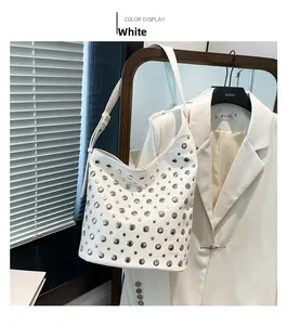 Détails d'un sac seau blanc style punk avec des clous argentés et une large bandoulière