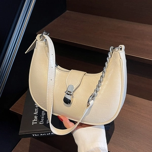 Detail of cream white half-moon shoulder bag with silver chain and magnetic buckle