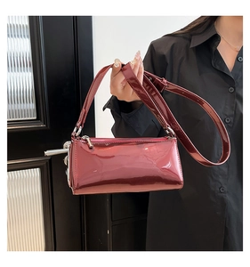 Detail of wine red patent leather baguette bag with shiny texture and silver zipper
