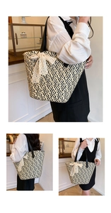 Close-up of woven straw tote bag with black zigzag pattern and white lace bow detail