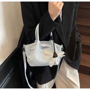 Détail d'un sac à main tressé avec breloque fleur blanche et sangle à boucle décorative