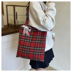 Detail of red and green plaid tote bag featuring a white lace bow and pearl chain