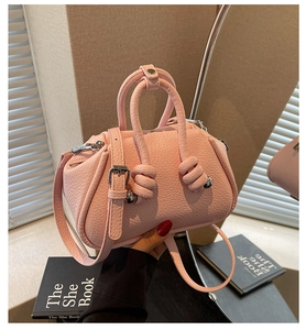 Dettaglio della trama in pelle rosa e del nodo del manico di questa borsa a mano