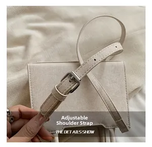 Détail de la bandoulière réglable avec boucle en métal sur un sac en tissu beige