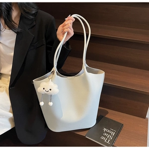 Close-up of a lychee grain bucket bag with a plush cloud pendant for daily commuting