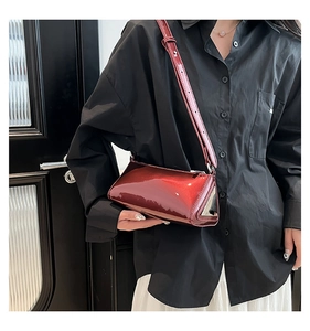 Detailed close-up showing the glossy wine red patent leather and triangle profile of the bag