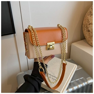 Detail view of contrast color crossbody bag with orange flap and gold chain strap