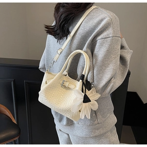 Gros plan détaillé sur la texture tressée du sac crème et son charme de fleur en tulle