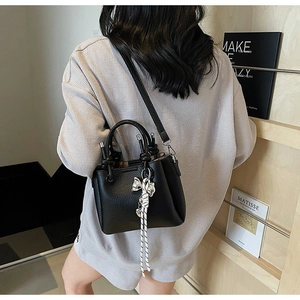 Litchi pattern bucket bag with bow pendant and knot, shown on model in lifestyle setting