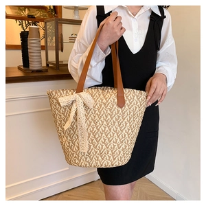 Detailed V-shape woven texture of large straw tote bag with lace bow and leather handles
