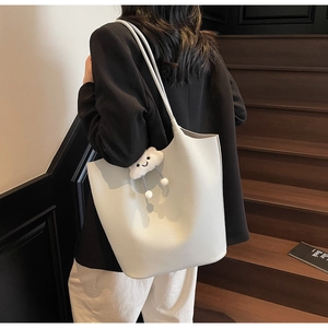 Detailed view of a white lychee leather bucket bag with a cute cloud charm on a strap