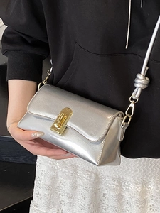 Minimalist silver crossbody bag with metallic finish and gold buckle on female model
