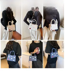 Détail des patchs cœur sur sacs carrés crème et denim avec bandoulières réglables