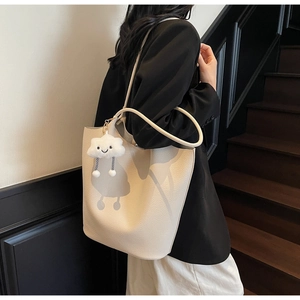 Detail of off-white lychee texture tote bag with a cute cloud pendant on a model