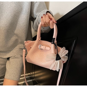 Détail du sac à main rose à texture tissée avec boucle en métal et breloque fleur blanche