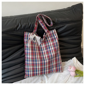Detail of red and blue plaid tote bag with delicate white lace bow and pearl charm