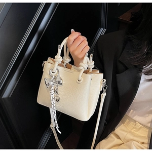 Detail of off-white lychee texture bucket bag with silver bow charm and striped scarf