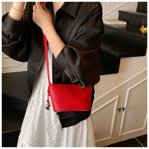 Dettaglio mini borsa a secchiello in pelle rossa con ciondolo a cuore su scale studio