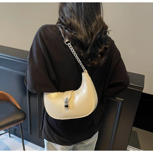 Detail view of cream crescent bag with silver chain strap and metal clasp on model