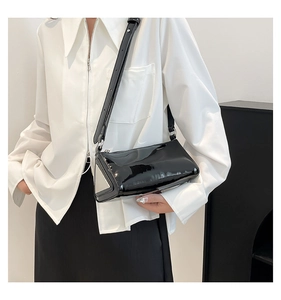 Detail of black glossy patent leather shoulder bag with silver triangular metal piece