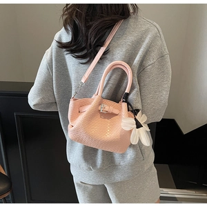 Texture détaillée du sac à main tressé rose en PU avec accessoire floral élégant