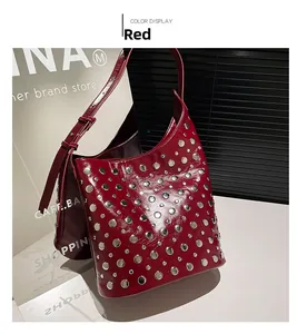 Gros plan détaillé du cuir PU rouge brillant avec des clous argentés sur un sac hobo