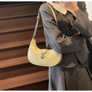 Detail of crescent shoulder bag with metallic chain strap and curved buckle on leather