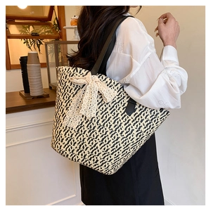 Detail shot of woven straw tote bag with elegant lace bow and black leather straps
