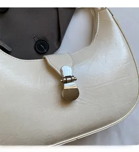 Close-up of creamy white PU leather crescent bag featuring textured surface and silver buckle