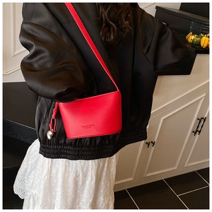 Dettaglio borsa a secchiello in pelle martellata rossa con scritta fashion e ciondolo
