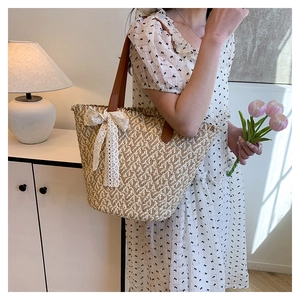 Detail of woven straw tote bag with brown leather handles and a large white lace bow