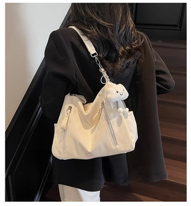 Détail du grand sac beige avec fermetures éclair latérales et breloque nuage en peluche