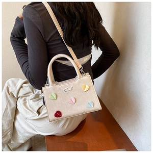 Sac bandoulière en toile beige avec écussons cœurs colorés présenté en situation réelle