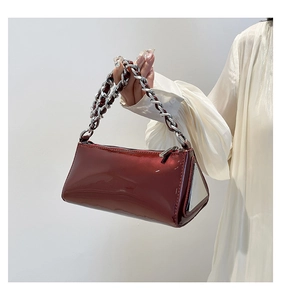 Detail view of glossy dark red patent leather bag with chunky silver chain handle