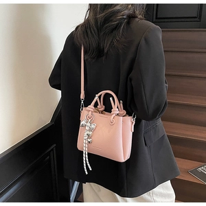 Lifestyle view of a pink litchi grain bucket bag with adjustable strap and heart charm