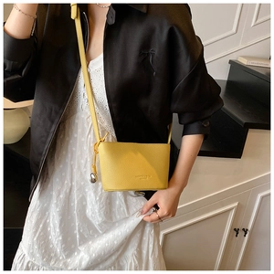 Mini borsa a secchiello gialla motivo litchi con ciondolo metallico e tracolla sottile