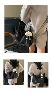 Détail d'un grand sac noir avec fermeture éclair argentée et pendentif nuage blanc