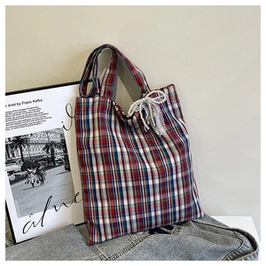Detail of checkered canvas tote bag with red, blue, white weave and pearl lace bow