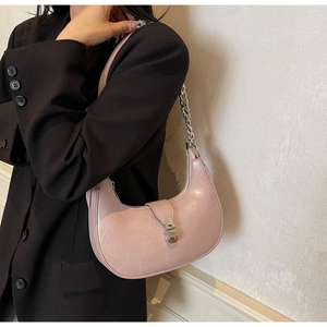 Pink metallic hobo bag with silver chain strap worn by model against light wall