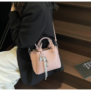 Pink lychee texture bucket bag featuring metal heart charm and woven bow detail