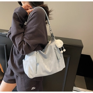 Vue détaillée d'un sac cabas bleu clair avec zips métalliques et pendentif en peluche