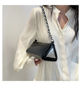 Detail of black patent leather triangle bag with silver chain and metal hardware decoration