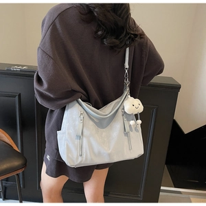 Détail macro du sac hobo argenté avec fermeture zippée et breloque nuage en peluche